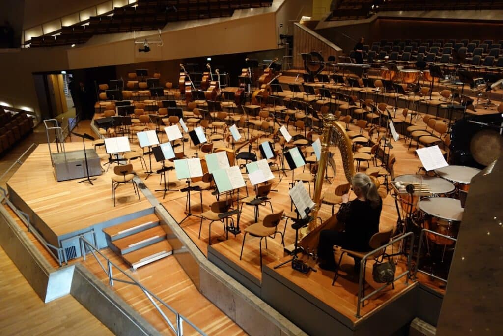 Close-up of a symphony conductor's hands moving gracefully with motion blur under dramatic lighting, symbolizing the orche...