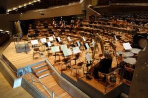 Close-up of a symphony conductor's hands moving gracefully with motion blur under dramatic lighting, symbolizing the orche...