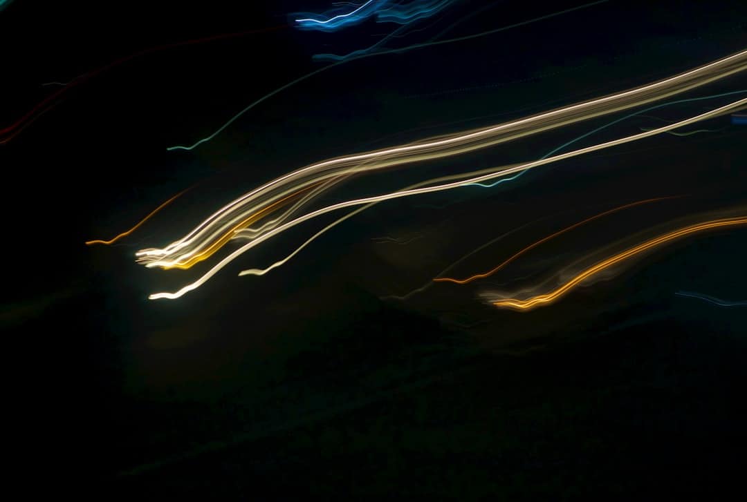 Abstract blue and white light trails moving quickly forward against a dark background, symbolizing cutting-edge technological progress and gaining an edge.