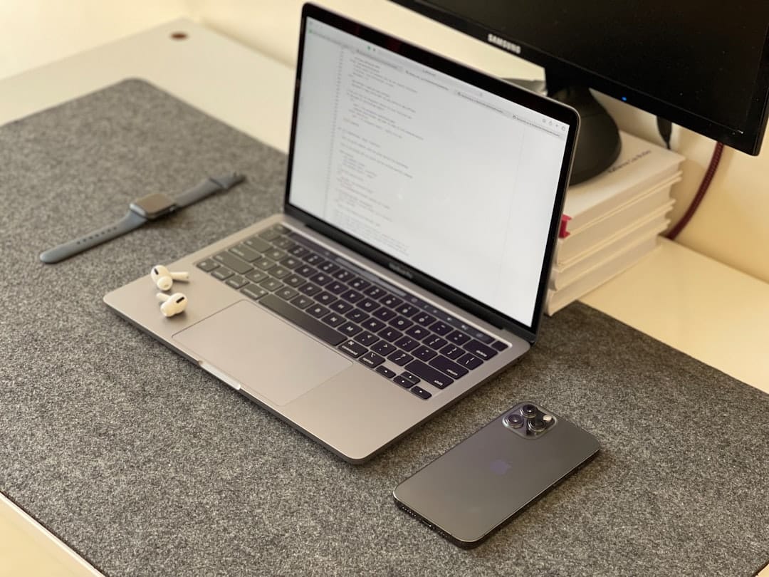 A clean, modern desk setup with a laptop open, a smartphone, and a set of house keys, illustrating the tools of a contemporary realtor.