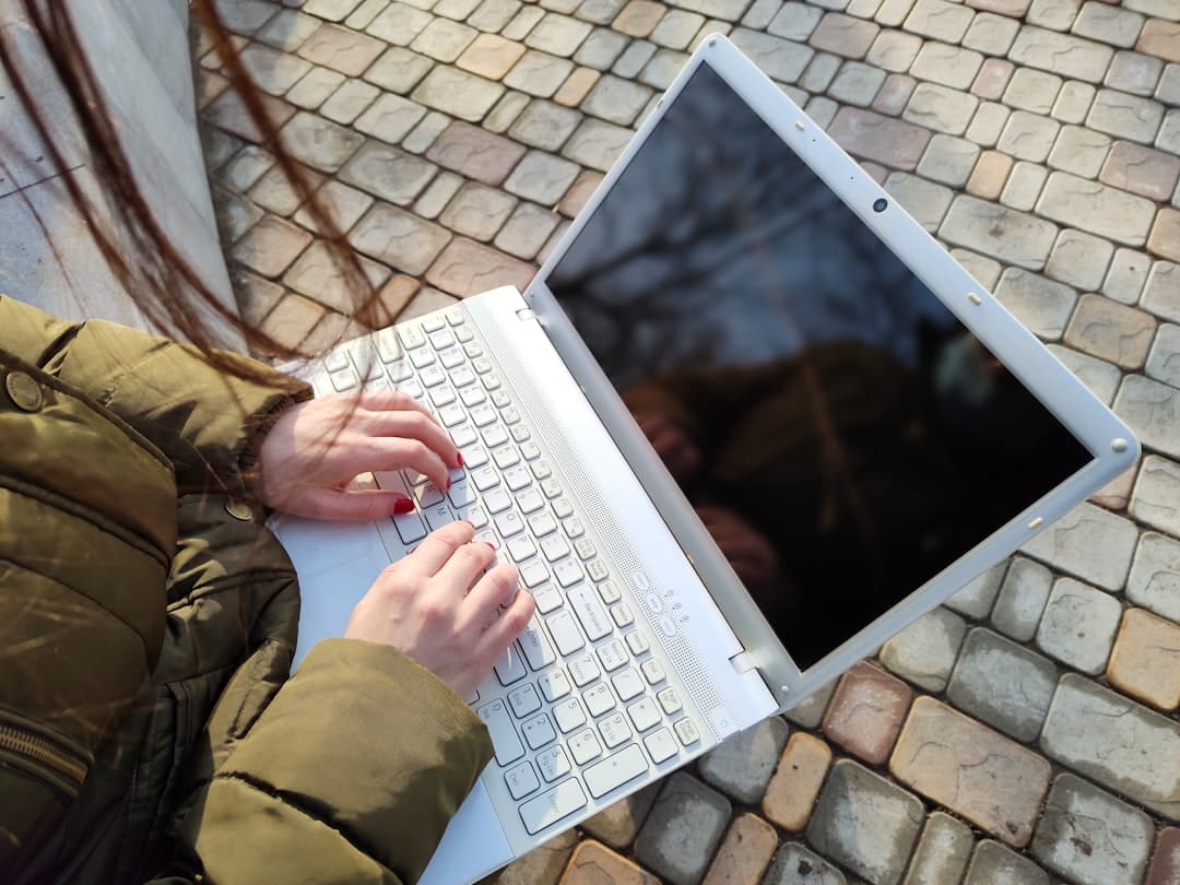 A person sits at a clean, organized desk with a cup of coffee, intently researching houses on a laptop screen that shows real estate listings.