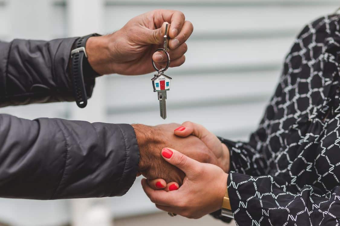 A person's hands signing a real estate contract on a bright, modern table, signifying the successful and straightforward closing of a home sale.