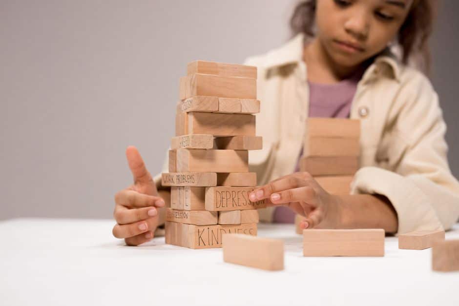 Close-up of a person's hands carefully placing a wooden block onto a larger, stable structure, representing the strategic, foundational work of a project-based SEO engagement.
