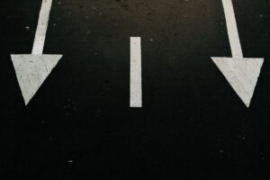 Minimalist signpost with two blank arrows pointing in opposite directions against a clear sky, symbolizing the strategic c...