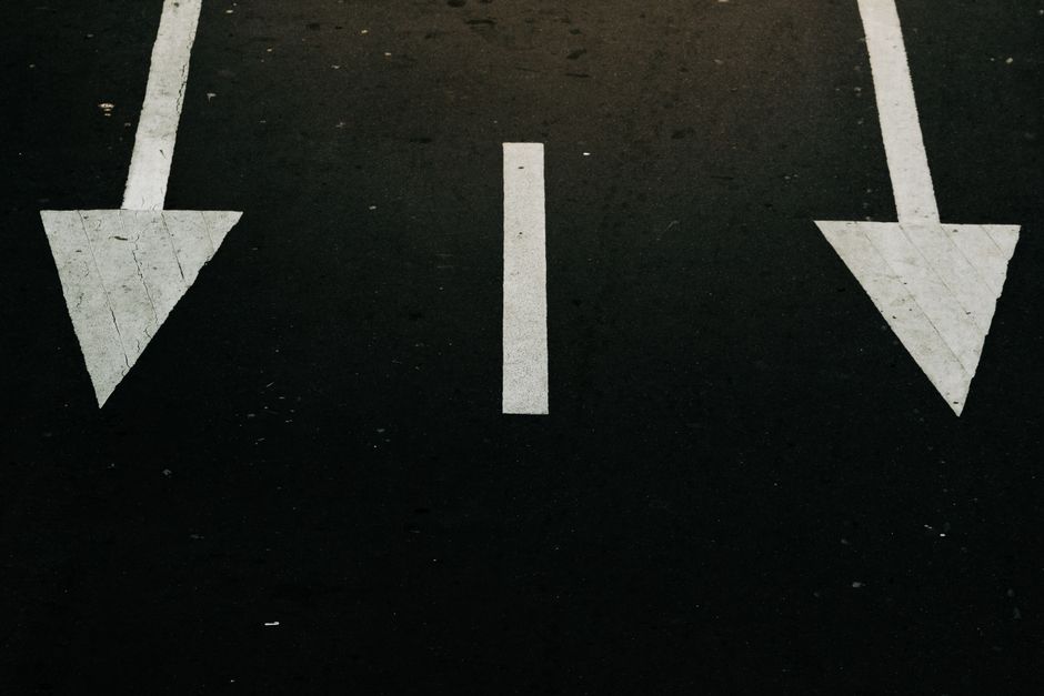 Minimalist signpost with two blank arrows pointing in opposite directions against a clear sky, symbolizing the strategic c...