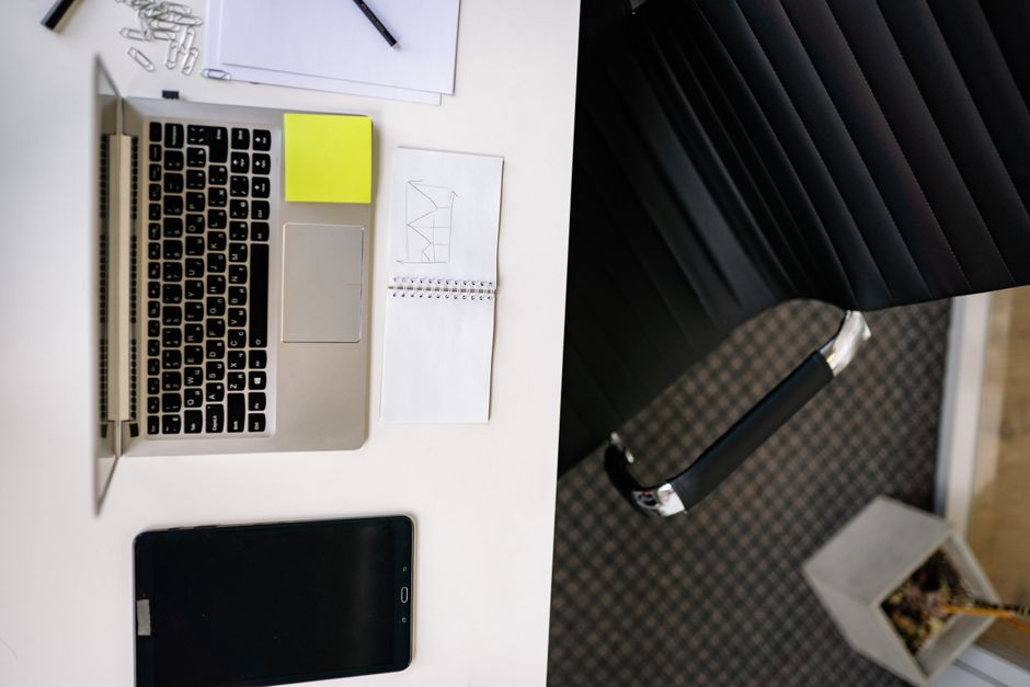 An overhead view of a minimalist and organized desk with a laptop, a notebook, and a pen, representing clear business strategy and planning.