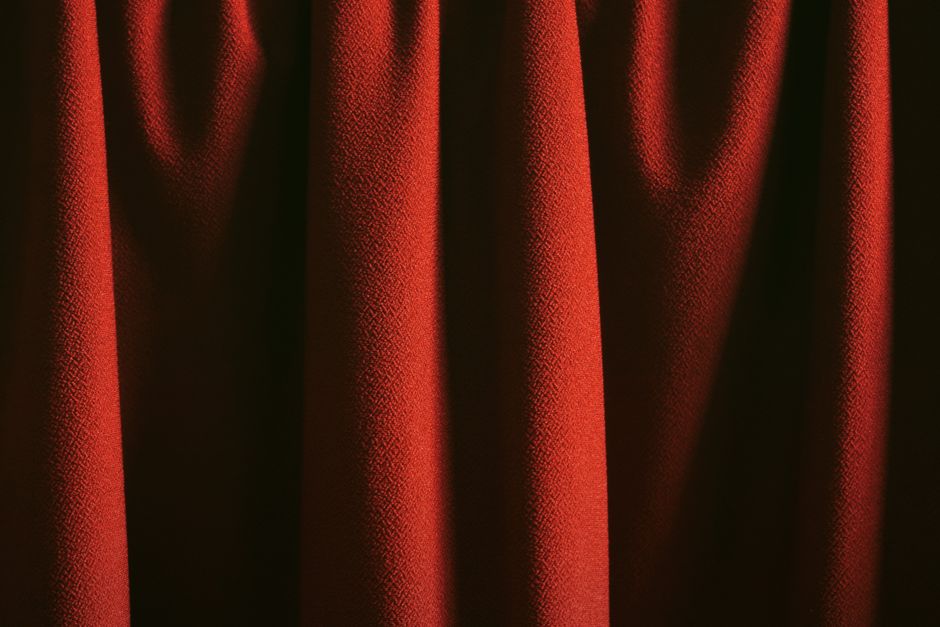 Person's hand pulling back a heavy, dark curtain, symbolizing the act of revealing the hidden secrets of SEO agency pricing.