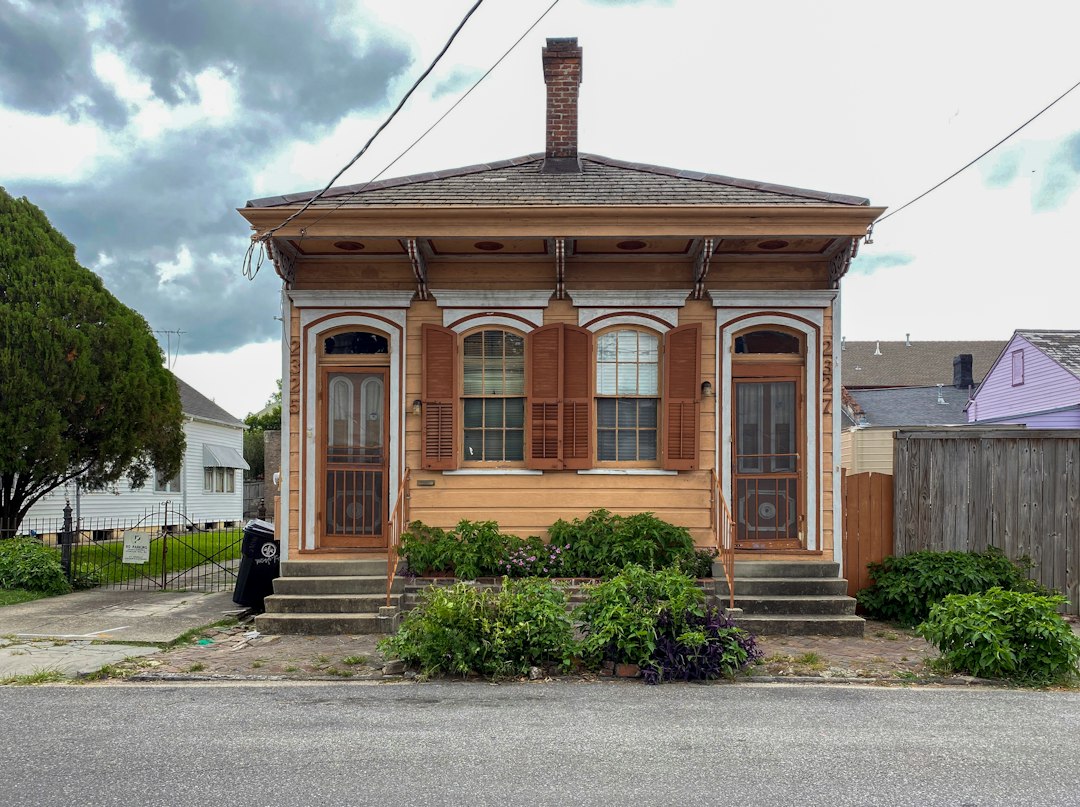 A classic New Orleans shotgun-style home sits under a bright, hot sun, representing the local climate challenges for homeowners.