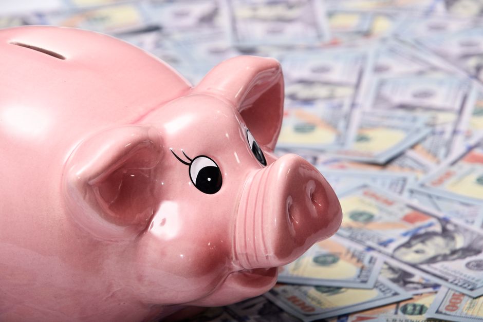 A miniature house model placed next to a piggy bank, representing the concept of saving money on home insurance.